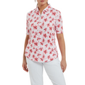 A woman wears a FootJoy Women's 1/4 Zip Short Sleeve Floral Shirt and white pants, standing with her arms relaxed at her sides.