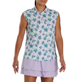 Front view of a model wearing a sleeveless floral golf top by FootJoy, featuring a green and blue floral pattern on a white base. Paired with a light lavender pleated golf skirt.