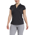 A woman wears a FootJoy Women's Cap Sleeve Print Shirt in Black Animal Print, standing against a white background and smiling slightly, with her arms relaxed at her sides and paired with light gray pants.