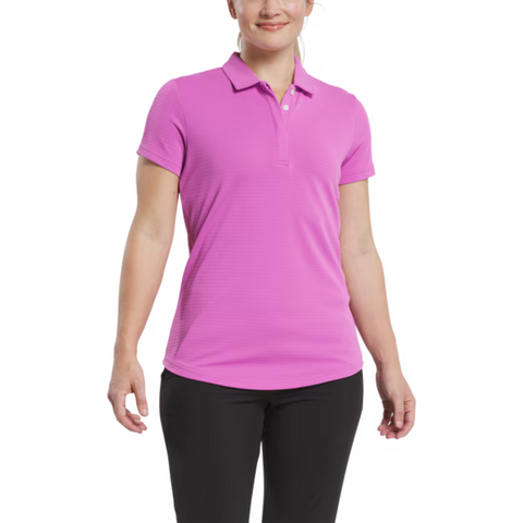 A woman in a FootJoy Women's Jacquard Short Sleeve Shirt in Berry and black pants stands against a white background, smiling softly with her arms at her sides. The shirt's performance stretch fabric delivers comfort and style for any occasion.