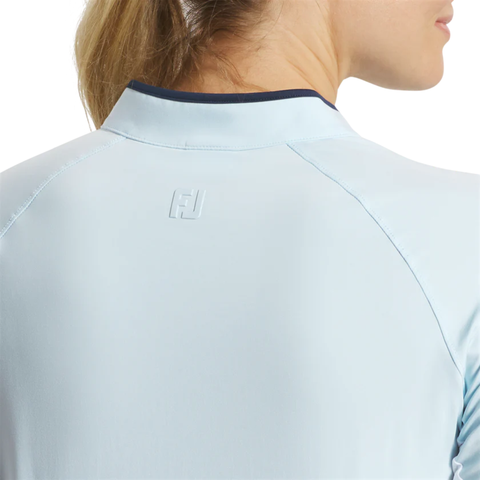 Close-up of a person wearing the FootJoy Women's Long Sleeve Sun Protection Shirt in Skyway/Navy, viewed from behind. The shirt features an embossed FJ logo below the collar and offers UV protection. Only part of the person's face is visible.