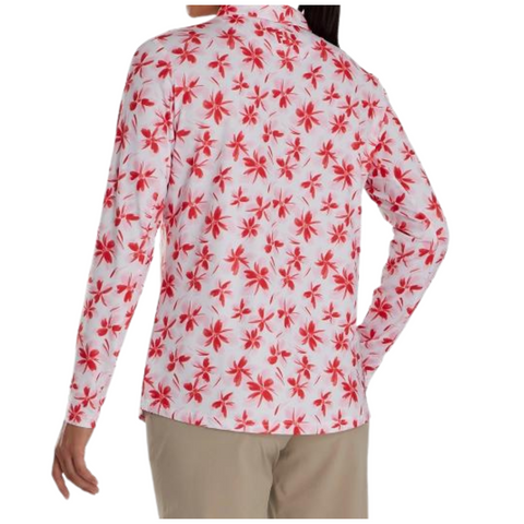 A person is shown from the back wearing a FootJoy Women's Long Sleeved Floral Shirt with a white background and red floral print, paired with beige pants. Their left hand rests on their hip.
