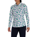 A person in a FootJoy Women's Long Sleeved Floral Shirt, featuring a blue and green floral pattern, paired with dark pants, stands against a plain white background.