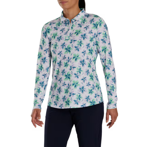 A person in a FootJoy Women's Long Sleeved Floral Shirt, featuring a blue and green floral pattern, paired with dark pants, stands against a plain white background.