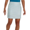 Wearing a teal top and a light plaid FootJoy Women's Performance Knit Skort, praised for moisture-wicking comfort, the person stands with arms relaxed by their sides, visible from the thighs down.