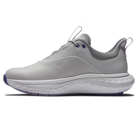 A side view of the FootJoy Women's Quantum Golf Shoes in Grey/White/Purple shows a light gray sneaker with purple accents, a thick white textured sole, and a seamless design, featuring OrthoLite FitBed cushioning for superior comfort.