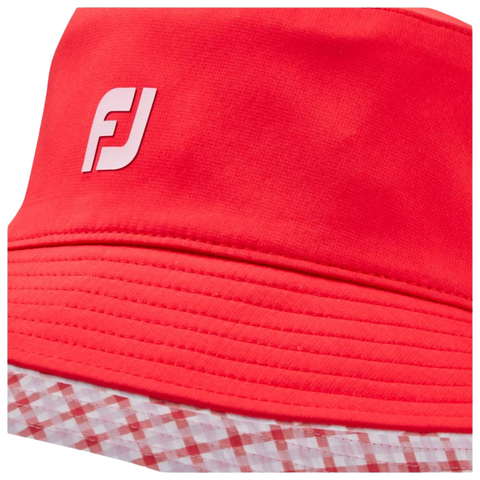 Close up detail of FootJoy red bucket hat with a white logo on the front. The hat is lined with a contrasting red and white checkered pattern, offering both 
 a reversible style and sun protection.