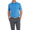 A man wears a FootJoy Lisle Dot Print Mens Polo in light blue, paired with gray pants and a gray belt. He stands with his hands in his pockets against a white background, his face partially out of frame.
