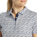 A woman wearing a FootJoy Women's Floral Print Short Sleeve Shirt, shown from the shoulders up, faces slightly to the side with a soft smile.