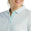 A woman smiles while wearing a FootJoy Women's Floral Print Short Sleeve Shirt. The light blue and white top with turquoise buttons is shown on her lower face and upper torso. Brand: FootJoy.