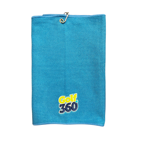 The Sporte Leisure Golf 360 Waffle Golf Towel is blue, includes a metal grommet and hook at the top, and features the Golf 360 logo in yellow and black near the bottom center.