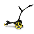 A black MGI ZIP X1 Motorised Trundler with large yellow-rimmed wheels and adjustable handle, powered by an 18-hole battery and offered with a free accessory pack, is displayed against a plain white background.