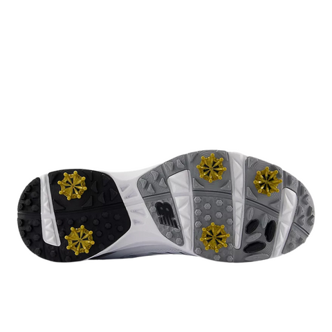 The image displays the sole of the New Balance Brighton V2 Men's Golf Shoes in White/Grey, featuring six yellow cleats and textured gray and black rubber patterns for advanced traction.
