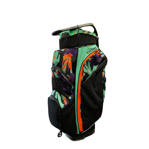 The Ogio 2026 Silencer Cart Bag | Tetra features a vibrant tropical leaf and flower design in green, orange, and purple, multiple zippered pockets, top handle, and anti-rattle club protection for convenience.