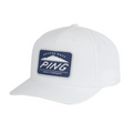 The PING Camelback Patch Cap by Ping is a white golf cap with a curved brim, featuring moisture-wicking fabric and a blue rectangular patch on the front that says Arizona Made PING Golf Company in white text.