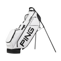 The Ping Hoofer Tour Stand Bag is a white golf bag with black accents, bold PING branding on the side, multiple zippered pockets for tour-level storage, and sturdy black stand legs to keep it upright.