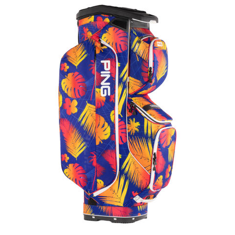 The PING Traverse Golf Cart Bag by Ping features a bold tropical pattern in blue, orange, and yellow with leaves and flowers. This lightweight bag offers multiple pockets, a 14-way divider, and PING vertically on the side.