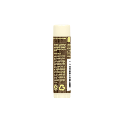 A beige tube of Sun Bum SPF 15 Sunscreen Lip Balm in Coconut (4.25g) stands upright with a brown label featuring product details, icons, a barcode, and instructions in white and yellow. The cap is securely closed.