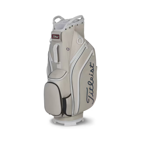 A Titleist Cart 14 Lightweight Golf Bag by Titleist in beige, featuring multiple zippered pockets and a black side handle with the brand logo on the side, stands upright against a white background.
