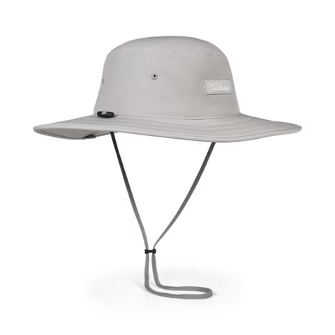 The Titleist Charleston Aussie Bucket Hat in Grey/White offers sun protection with a wide brim, chin strap, and ventilation eyelets. Features a sleek rectangular Titleist logo patch—ideal as a stylish golf accessory.