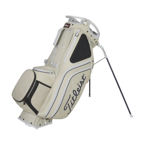The Titleist Hybrid 14 Golf Bag in beige with black and white accents features a lightweight build, 14-way top divider, multiple zippered compartments, and stands on two extended legs.