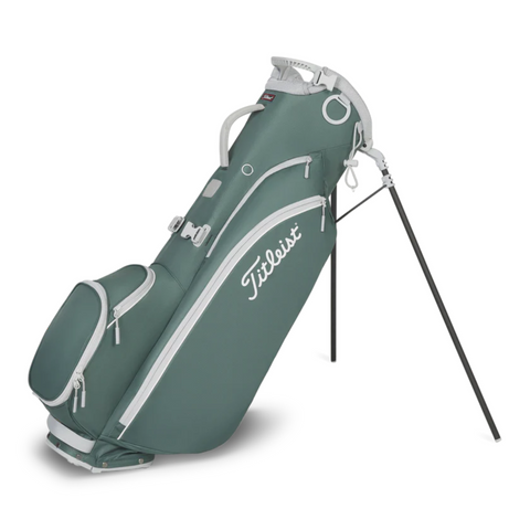 The Titleist Players 4 Carbon Stand Bag 2025 stands upright on carbon fiber legs, featuring green and white accents, multiple zippered compartments, a carrying handle, and an ultra-lightweight design for convenience and style.
