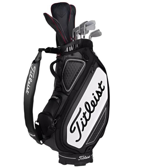 The Titleist Tour Golf Bag | Black/White stands upright, filled with golf clubs, featuring the bold Titleist logo on the side and strap for a stylish, professional look.