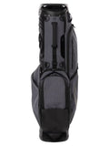 The Travis Mathew Golf BYOB Stand Bag in heather dark grey stands upright, featuring multiple zippered compartments, a padded top for club protection, sturdy handles, and a sleek, modern Travis Mathew design.