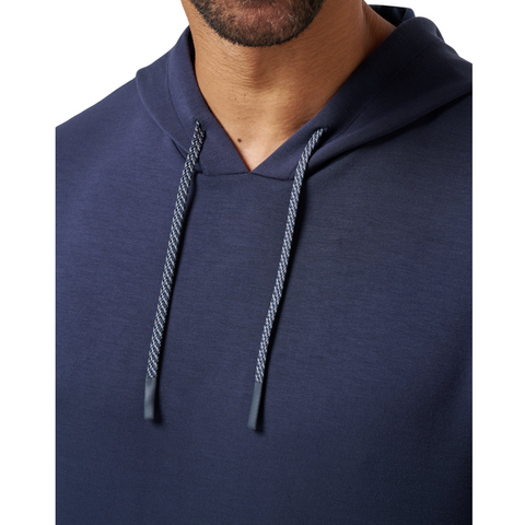 A close-up shows a man wearing the TravisMathew Fibercloud Men's Hoodie in Total Eclipse, featuring grey drawstrings. Only his lower face, neck, and upper chest are visible.