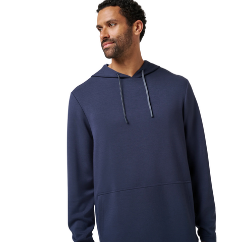 A man with short curly hair and a beard wears the TravisMathew Fibercloud Men's Hoodie in Total Eclipse, looking to his left against a plain white background.