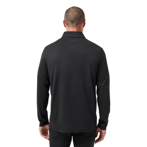 A man with short hair is seen from the back wearing a Travis Mathew Heater Pro 1/4 Zip Men’s Pullover in black, paired with black pants, standing against a white background.