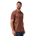 A man with short brown hair and a beard wears the Travis Mathew Mens Featherweight Ticket Polo Shirt in Maple, featuring a subtle leaf pattern. He stands against a white background, looking left with one arm relaxed at his side.