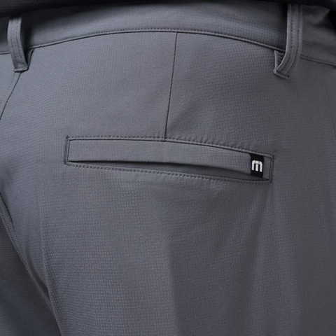 Close-up of the back pocket on Travis Mathew Open To Close Men's Jogger pants in gray, featuring a small black tag with a white m logo near the pockets top.