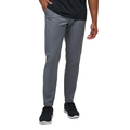 A man stands against a white background wearing Travis Mathew Open To Close Men's Jogger pants in gray, paired with a black shirt and black sneakers.