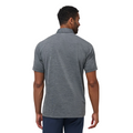 A man stands facing away, showing the back of the moisture-wicking TravisMathew The Heater Pro Mens Polo in heather gray, paired with navy pants, against a plain white background.