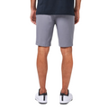 A person stands with their back to the camera, wearing a navy shirt, Travis Mathew Wanderlust Mens Shorts in light gray, and white sneakers with black accents.