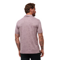 Back view of the TravisMathew New Destination Polo in muted purple, worn by a model, featuring a classic collar, short sleeves, and a subtle heathered texture.