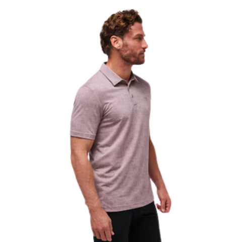 Side view of a model wearing the TravisMathew New Destination Polo in muted purple, featuring short sleeves and a three-button placket, highlighting the relaxed fit and subtle heathered texture.