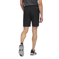 The Adidas Ultimate365 8.5-Inch Men's Golf Shorts in black, worn by a model and shown from the back, feature a back pocket with the Adidas logo above it, paired with black Adidas golf shoes.