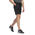 The Adidas Ultimate365 8.5-Inch Men's Golf Shorts in black, worn by a model, feature a tailored fit with side pockets and a belt, paired with black Adidas golf shoes.