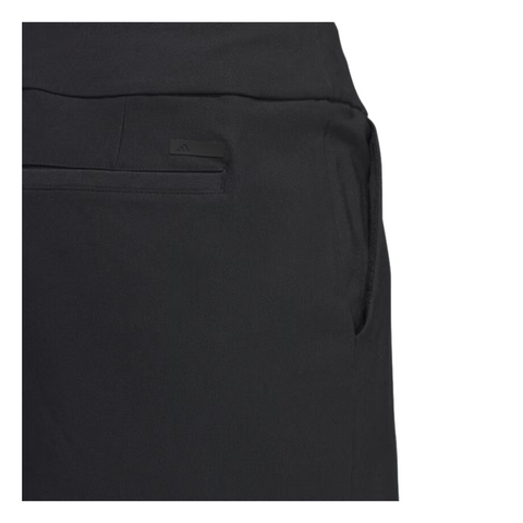 Close-up of the back detail of the Adidas Ultimate365 Solid Women's Skort in black, showing a discreet back pocket with a horizontal slit design. A small Adidas logo is subtly embossed near the pocket. The fabric appears smooth and structured, with a simple, minimalist finish.