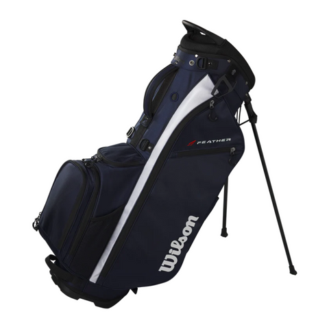 The Wilson 2025 Feather Stand Bag, in navy blue with white and black accents, stands on its extended legs. This ultra-lightweight golf bag includes multiple zippered compartments and features Wilson branding on the side.
