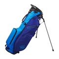 The Wilson Exo Lite Stand Bag in Dark Blue/Light Blue stands upright on extended metal legs, featuring a 5-way top, multiple zippered pockets, a shoulder strap, and the WS logo near the base.