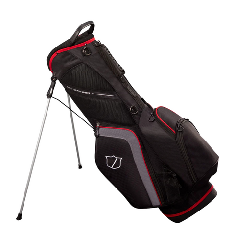 The Wilson Lite Stand Bag by Wilson, in Black/Charcoal/Red, features multiple zippered pockets, a side logo, an easy-carry handle, and silver legs with an automatic stand for upright support.