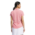 A woman with long dark hair in a ponytail is seen from behind, wearing a light pink Adidas Womens Ottoman Short Sleeve Polo Shirt and a white skirt, standing against a plain white background.