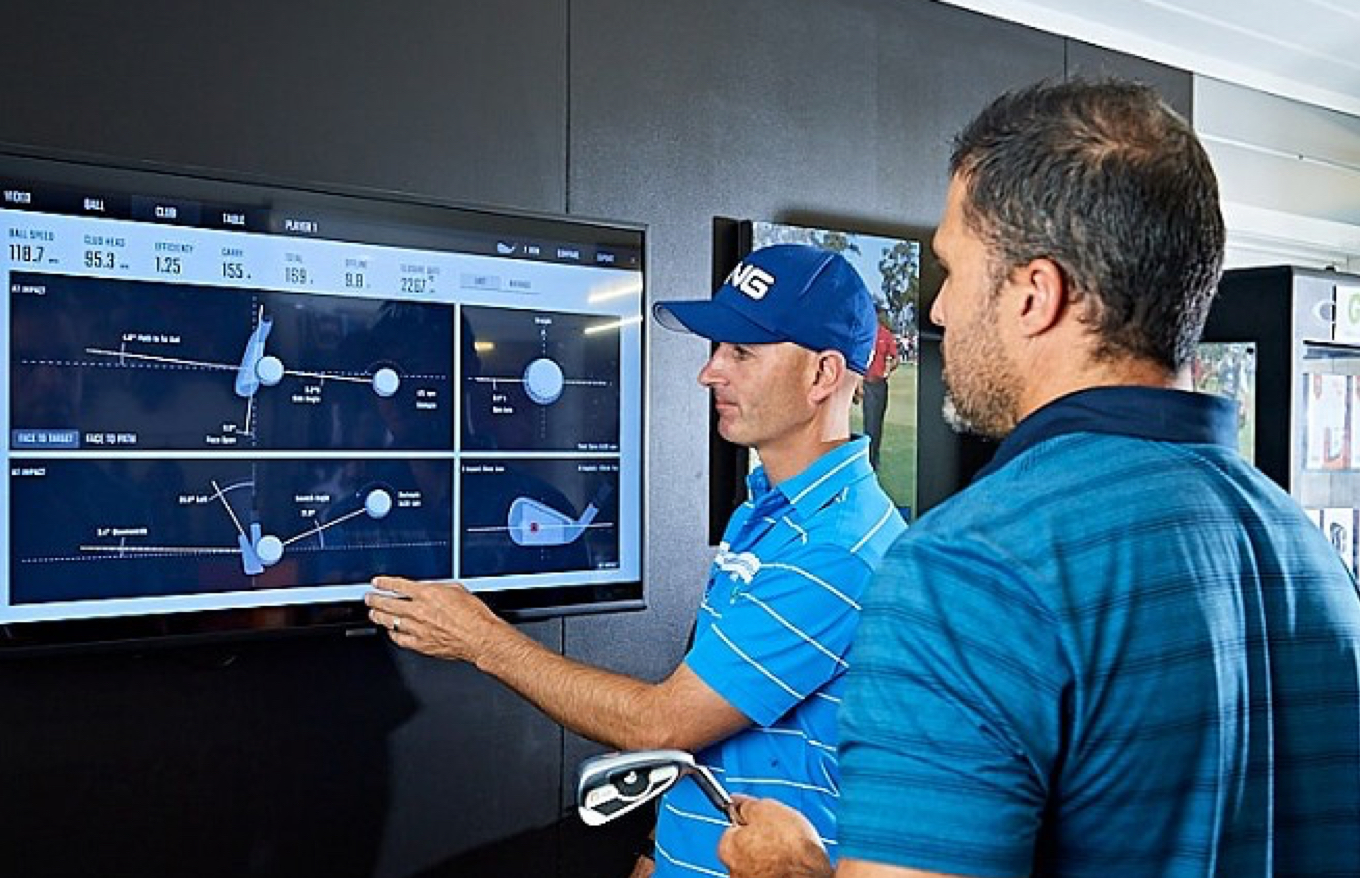 Two male golfers look at a screen showing a visual analysis of a golf club swing