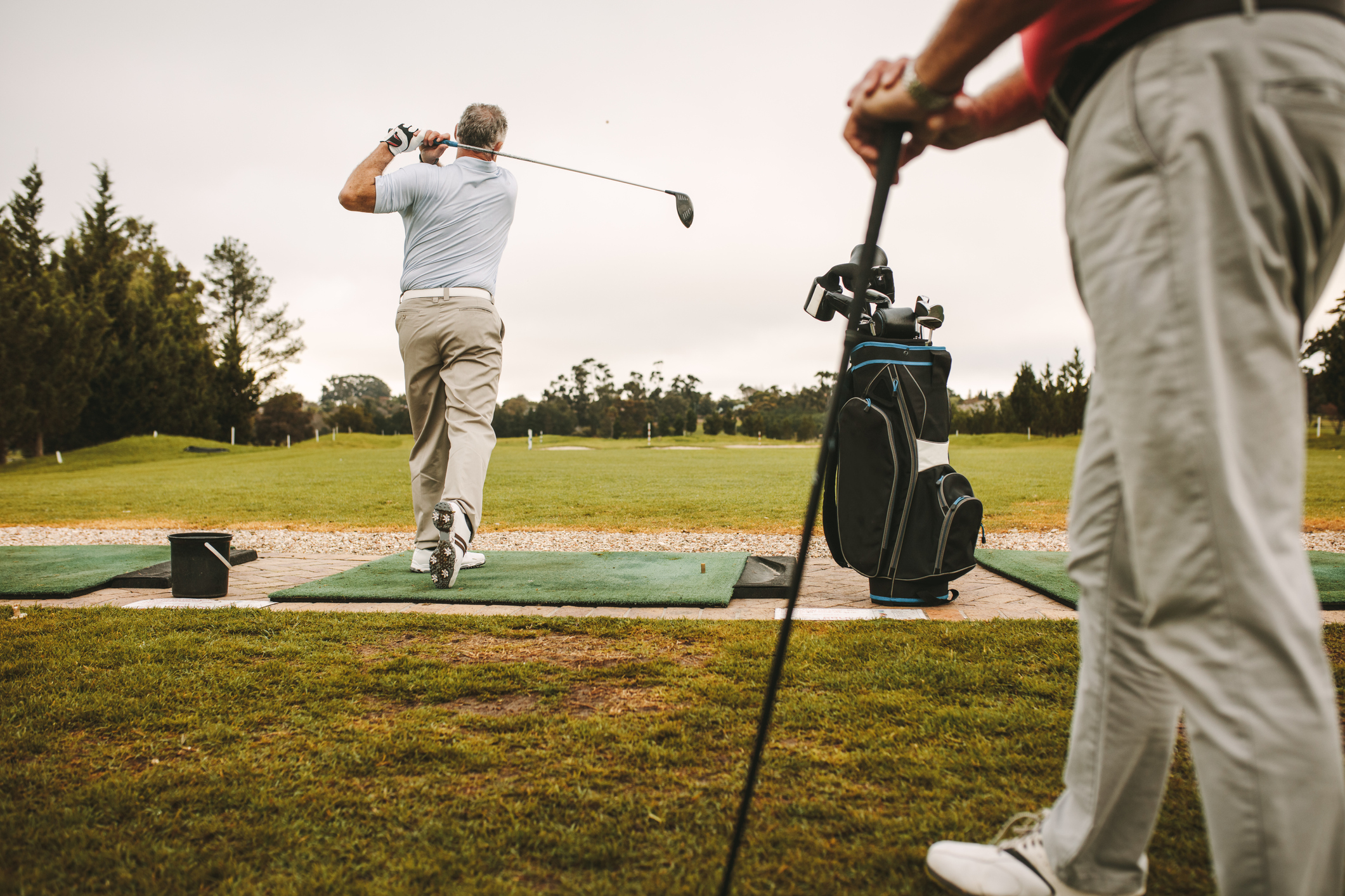 An Image of Two Men at a Driving Range.