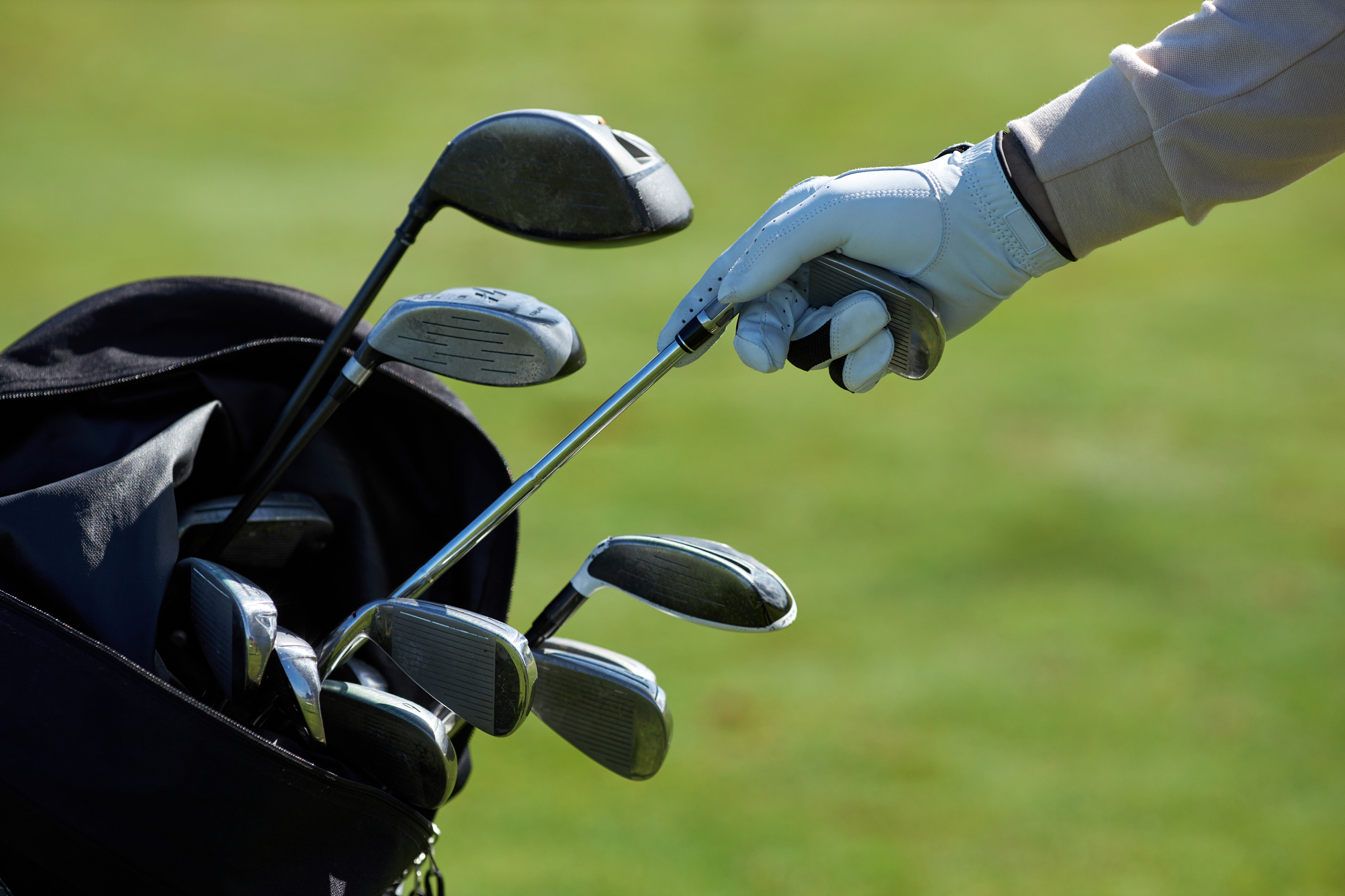 Closeup of golf player choosing club from a golf bag.