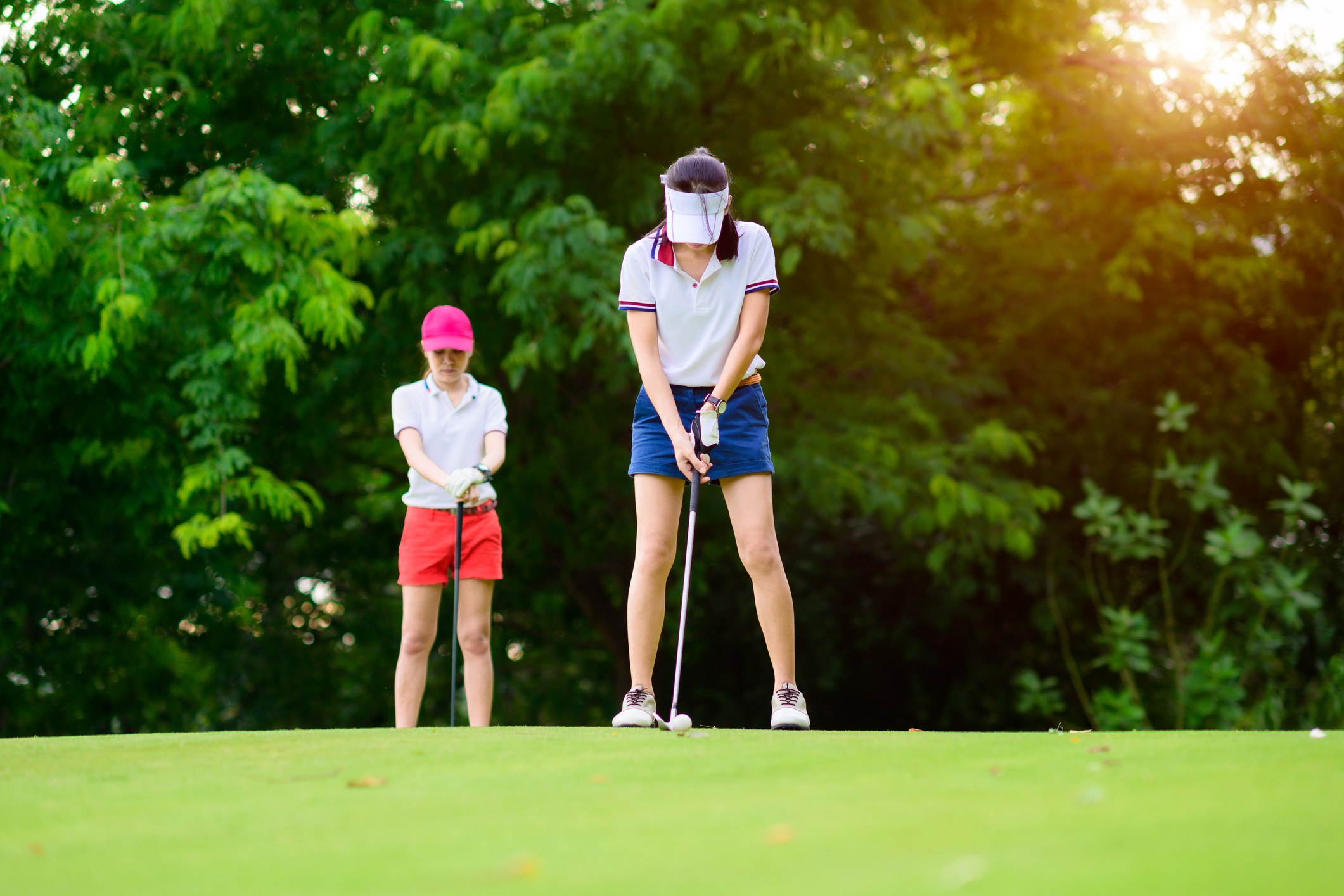 Female golf players playing golf.